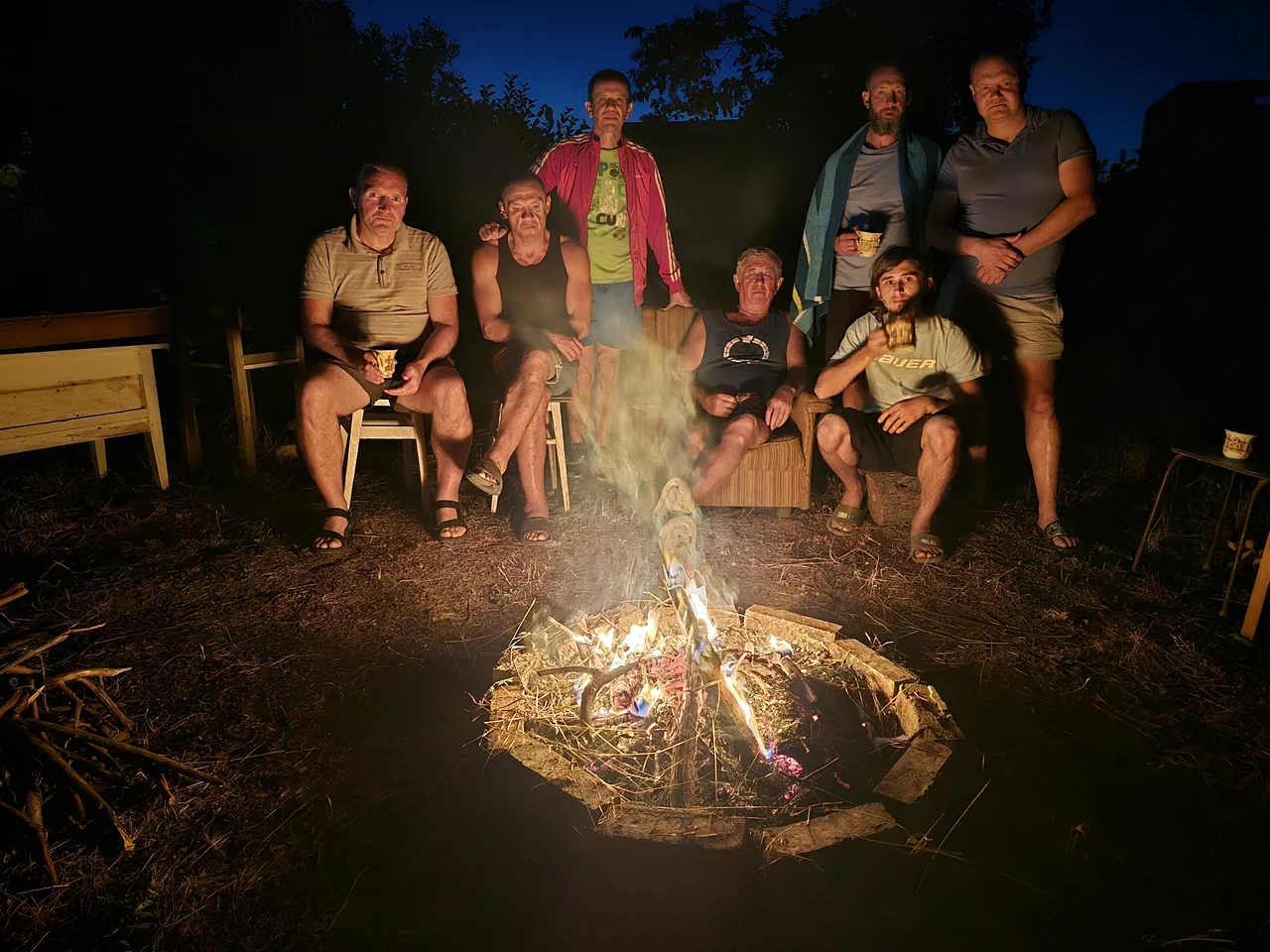 People gathered around a fire outdoors in the evening